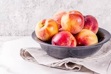 Raw fresh peaches in bowl on grey concrete background copy space