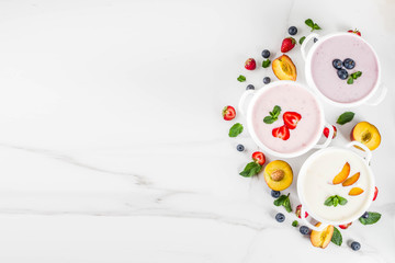 Obraz na płótnie Canvas Summer healthy diet dinner, vegan food, dessert, various sweet creamy fruit & berry soups - strawberry, peach, blueberry, white marble background copy space above