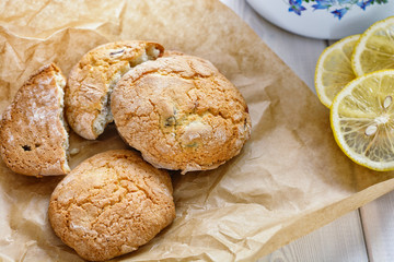 The cookie on the paper mat is next to the slices of lemon are on the table