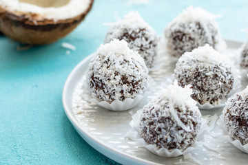Cooking at home: rolling homemade chocolate candies in coconut flakes