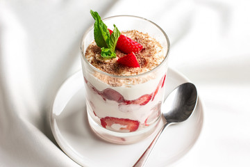 Healthy dessert in glass with fresh strawberries and cream yogurt on white background