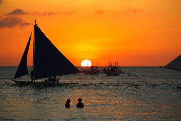 Silhouette of sailboats and people at sunset on White Beach in Boracay, Philippines. Summer vacation, leisure activity, holidays travel destination concepts