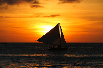 Fototapeta na wymiar Silhouette of sailboat at sunset in Boracay White Beach, Philippines. Leisure activity at twilight. Summer vacation, relax, travel destination concepts