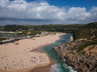 Aerial view from a beach with a river flows out to the Ocean. Foz do lizandro beach in ericeira,...