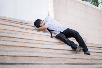 Asian businessman professional failed or upset in his job and sitting on staircase. Business problem concept.