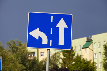 A road sign indicating the direction of the roads. The road to the left and the road straight