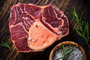Raw beef steak osso bucco on cutting board.