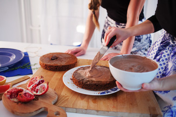 Home confectionery. Two girls making a cake on the kitchen.