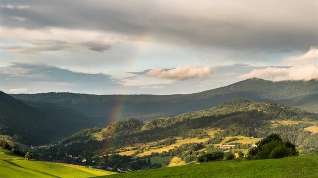 Rainbow over green rural landscape Time lapse