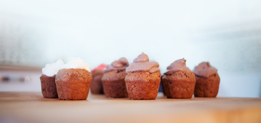 Chocolate muffins on the desk. Cupcakes with different creams. 