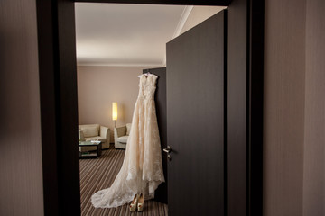 Marriage. Beige beautiful wedding dress with plume on hanger. In the room, indoors.
