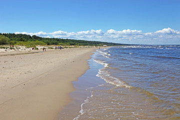 Walking on the shore of a beautiful sandy beach with forest on background, Baltic Sea, Jurmala, Latvia