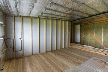 Room under construction and renovation with silver aluminum foil on walls and ceiling, oak floor...