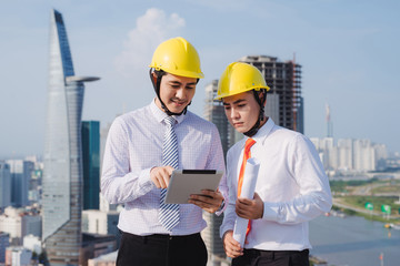 View of Two workers working outside with a tablet on a construction site