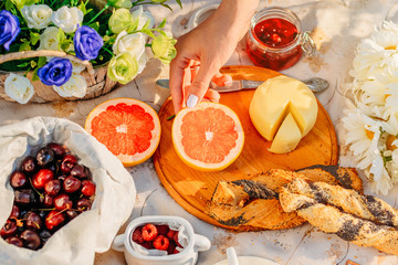 Picnic at sunset in park. Fruits, cheese an croissants on tablecloth