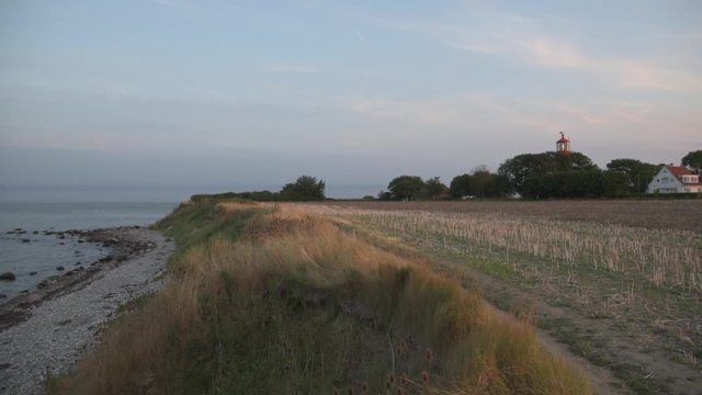 lighthouse on baltic sea high coast against sea in evening light on summer day