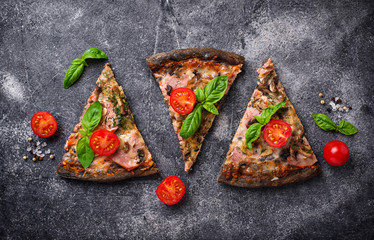 Pieces of  black pizza with tomatoes and basil