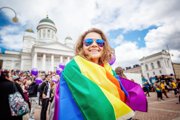 Beautiful young happy woman with a rainbow flag, symbol of the LGBT community on a pride in a...