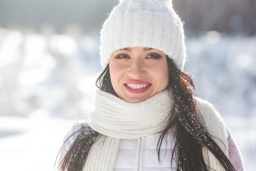 Close up portrait of young beautiful woman in the winter wood. Attractive lady smiling at camera
