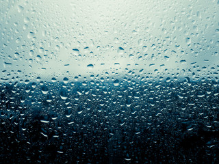 Water drop on the glass of windows background, raining on the glass off window city for background.