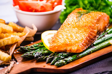 Fried salmon with french fries on wooden table 
