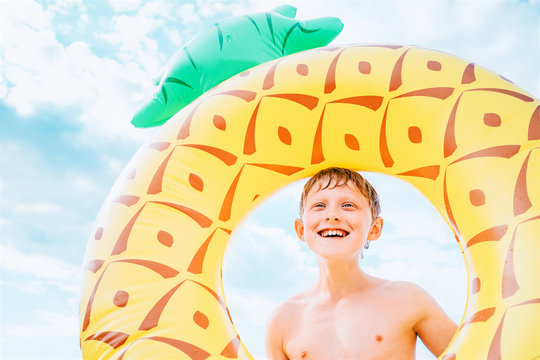 Happy smiling boy portrait with big inflatable pineapple ring