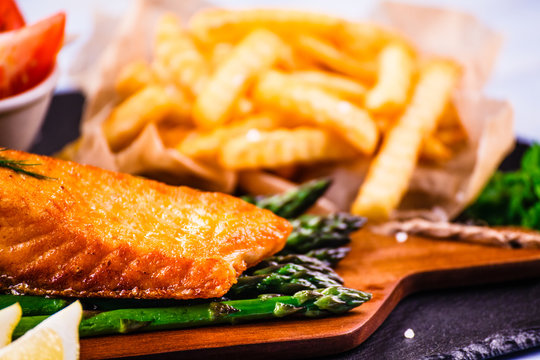 Fried salmon with french fries on wooden table 