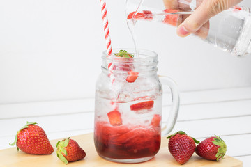 Fresh strawberry syrup and ice cube with soda for summer time on white wooden table background and strawberry fruits with copy space. Special taste of juice.