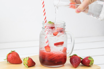 Fresh strawberry syrup and ice cube with soda for summer time on white wooden table background and strawberry fruits with copy space. Special taste of juice.