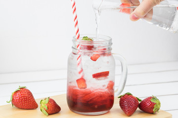 Fresh strawberry syrup and ice cube with soda for summer time on white wooden table background and strawberry fruits with copy space. Special taste of juice.
