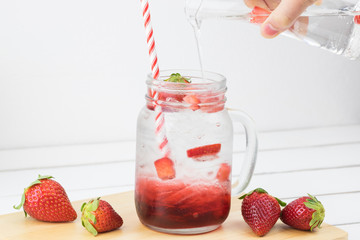 Fresh strawberry syrup and ice cube with soda for summer time on white wooden table background and strawberry fruits with copy space. Special taste of juice.