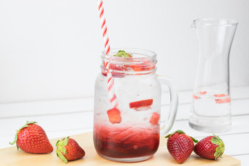 Fresh strawberry syrup and ice cube with soda for summer time on white wooden table background and strawberry fruits with copy space.