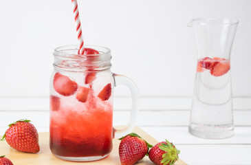 Fresh strawberry syrup and ice cube with soda for summer time on white wooden table background and strawberry fruits with copy space.