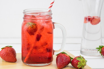 Fresh strawberry syrup and ice cube with soda for summer time on white wooden table background and strawberry fruits with copy space.