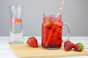 Fresh strawberry syrup and ice cube with soda for summer time on white wooden table background and strawberry fruits with copy space.