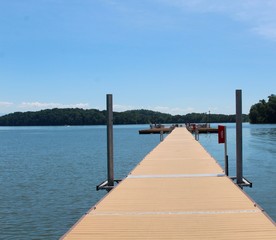 Obraz premium The long wooden dock at the lake on a sunny day.