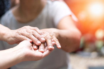 Caregiver, carer hand holding elder hand woman in hospice care. Philanthropy kindness to disabled...