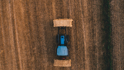 aerial view of harvest field with tractor moving hay bale around © Scenessence