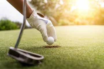 Hand putting golf ball on tee in golf course