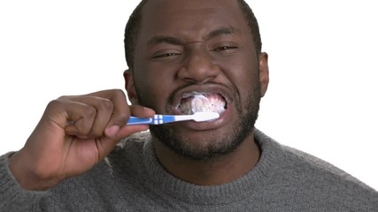 Black man brushing teeth. Process of cleaning teeth by dark skinned man on white background. Concept of oral hygiene and dental care. - Powered by Adobe