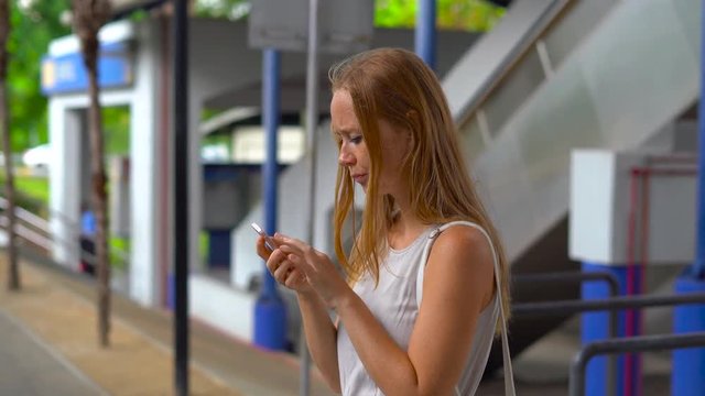 Young woman on a street lost in big city, trying to search through the map on her phone and book a taxi