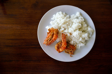 Rice and shirmp fried garlic in a white dish, which is plance on a wooden table, is a simple but...