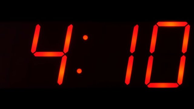 Close up of huge black,dark clock digital display,screen showing time between 4:00 AM or PM and 4:59 and beyond in big red digits