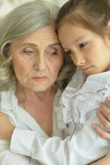 sad grandmother and granddaughter hugging
