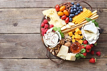 Poster Cheese platter with fresh berries and nuts on a rustic wooden table. Overhead view. © losangela