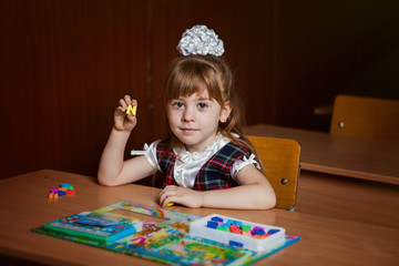 the girl teaches letters at her desk in the classroom