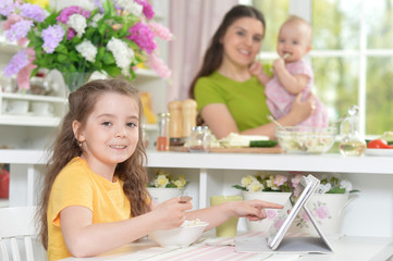 Obraz na płótnie Canvas Cute little girl eating fresh salad at kitchen table