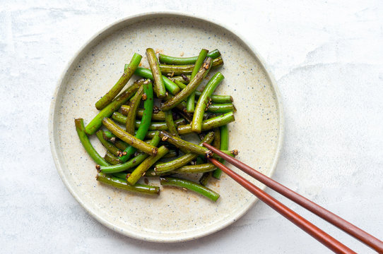 Eating grilled garlic scapes salad. Traditional Korean Chive Salad (Buchu Muchim). Top view. 