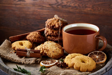Christmas teatime with oatmeal, chocolate biscuits, and spices, on wooden background, close-up, selective focus.