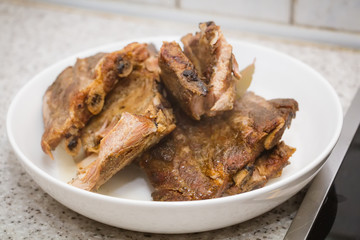 Brown fried meat ribs in white bowl on the table